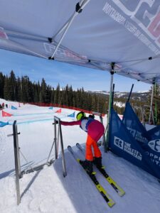 Ali Gregory at ski race start gate with Arctica Pinnacle Race Suit