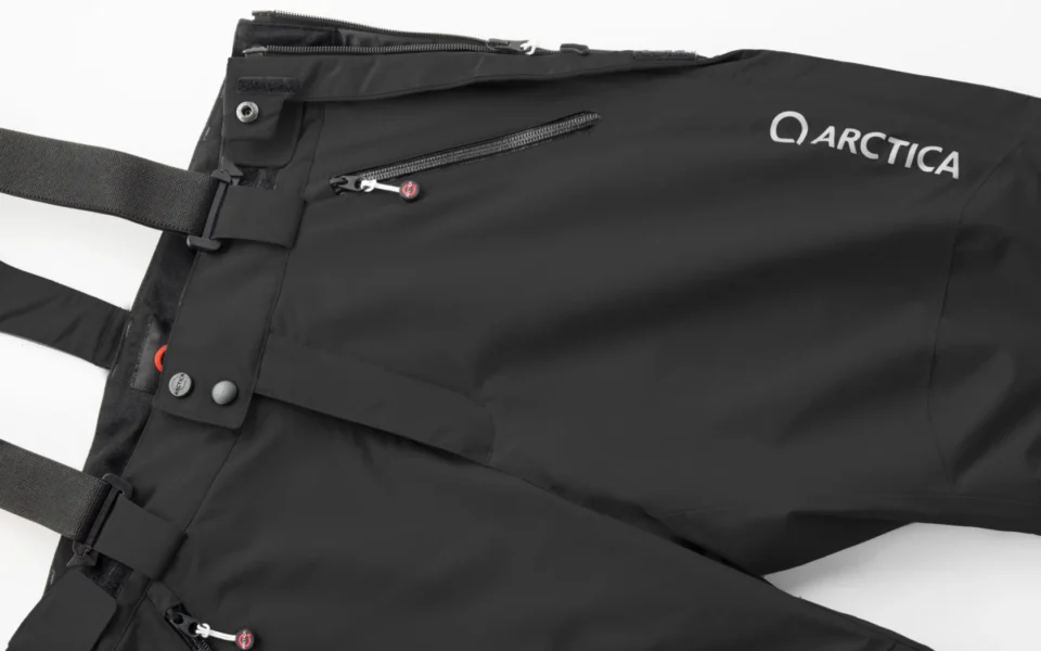 Close-up of the Arctica Side Zip Ski Pants 2.0 in Black showing the waistband, suspenders, zip pocket and logo.