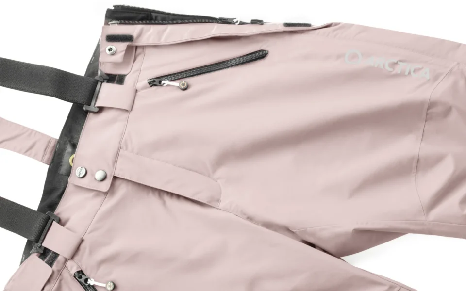 Close-up of the Arctica Side Zip Ski Pants 2.0 in Blush showing the waistband, suspenders, zip pocket and logo.