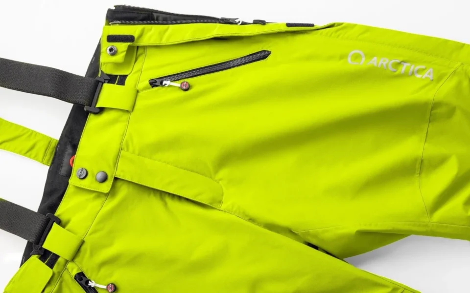 Close-up of the Arctica Side Zip Ski Pants 2.0 in Optic Yellow showing the waistband, suspenders, zip pocket and logo.