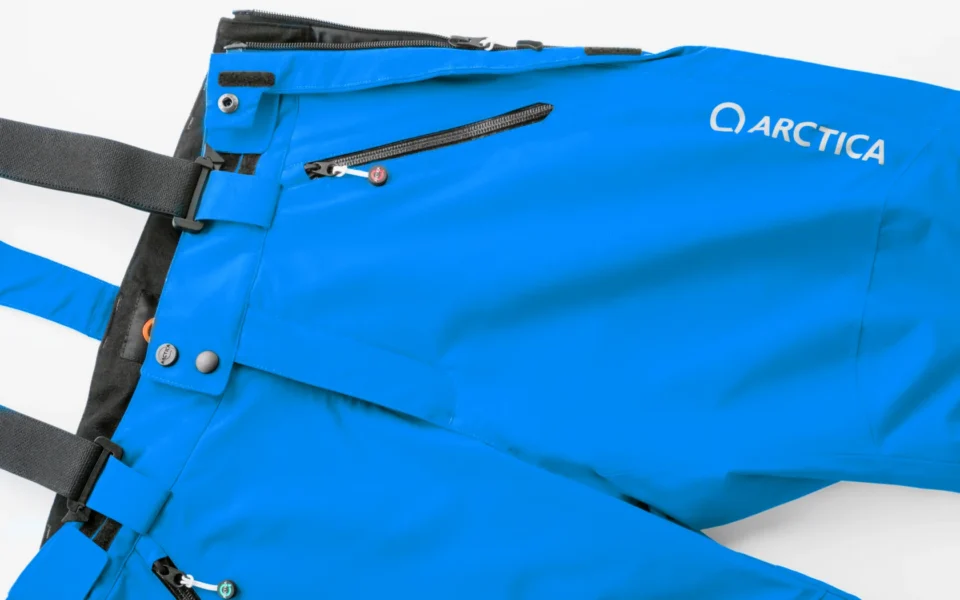 Close-up of the Arctica Side Zip Ski Pants 2.0 in Royal showing the waistband, suspenders, zip pocket and logo.