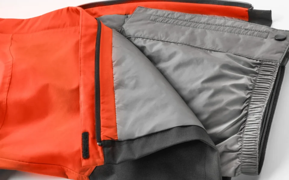 Close-up of the Arctica Side Zip Ski Pants 2.0 in Tangerine opened to show the gray lining.